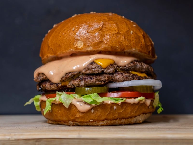 Double cheeseburger stacked with lettuce, tomato, pickles and burger sauce