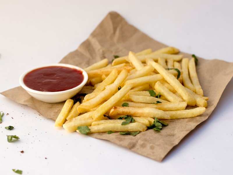 Chip-shop chips served on paper with a pot of tomato ketchup
