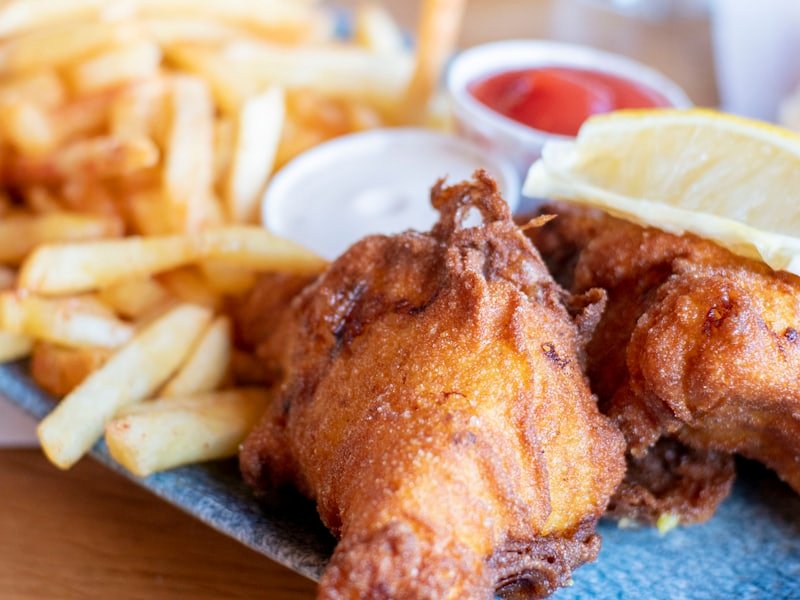 Battered haddock fillets with chips, a lemon wedge and dipping sauces