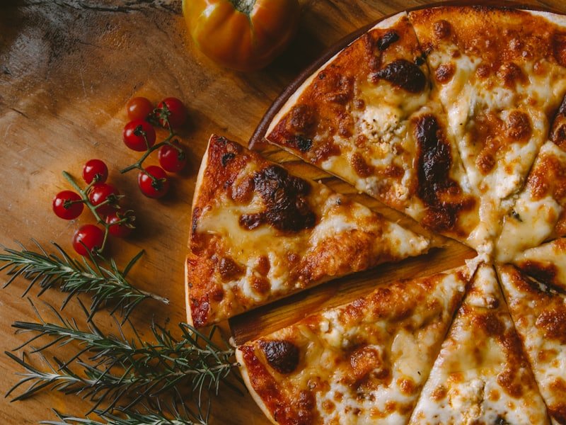 Stone-baked cheese and tomato pizza cut into slices on a wooden board