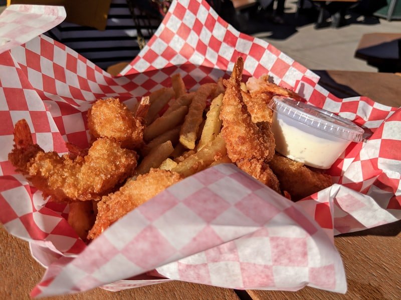 Golden breaded scampi pieces in a paper-lined basket with dip